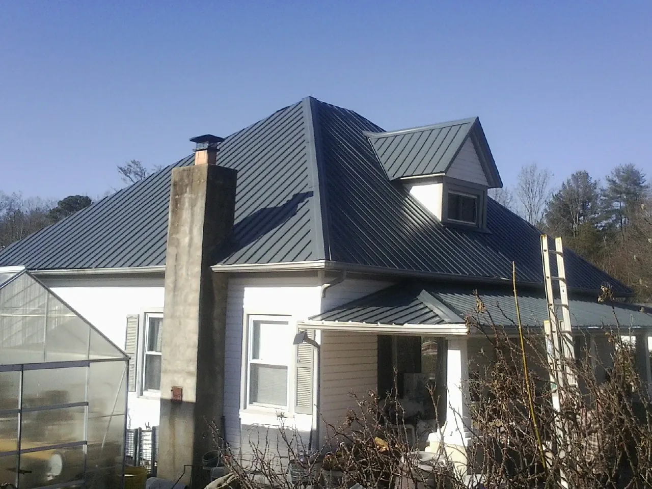 Dark blue standing seam metal roof on a white farmhouse with dormer — Slate & Tile Roof Repair by Roofing Brothers in Tehuacana