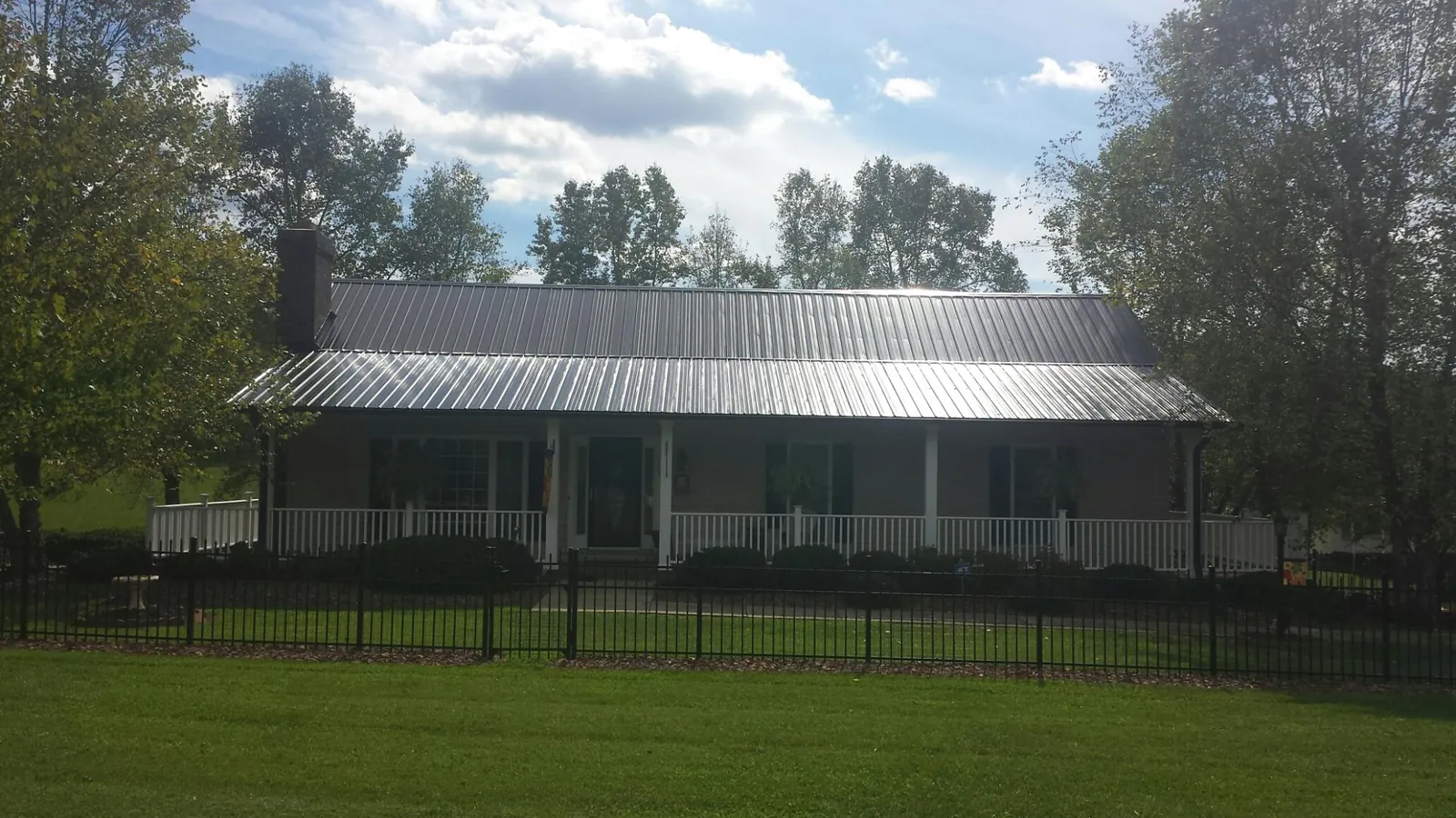 Gray metal roof on a brick ranch with a full width front porch — Gutter Guard Installation work by our crew in Tehuacana