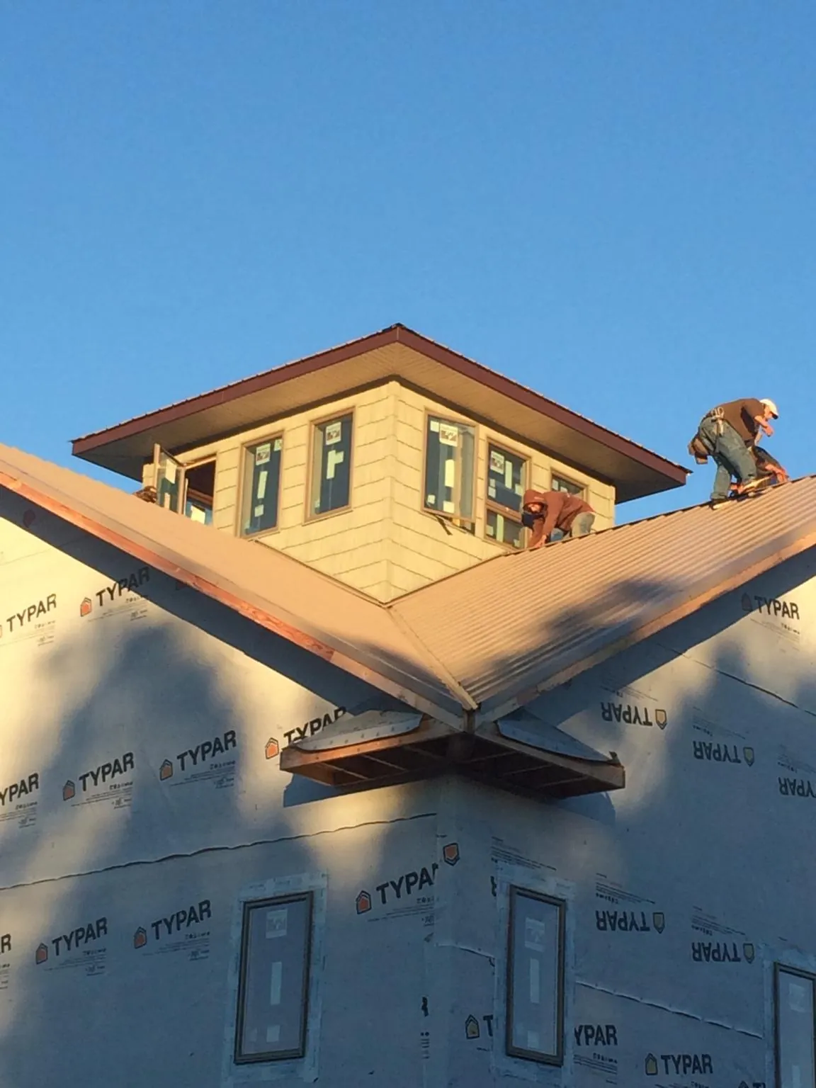 Roofers working around a rooftop cupola on a new metal roof at sunset — Roof Waterproofing in Tehuacana by Roofing Brothers
